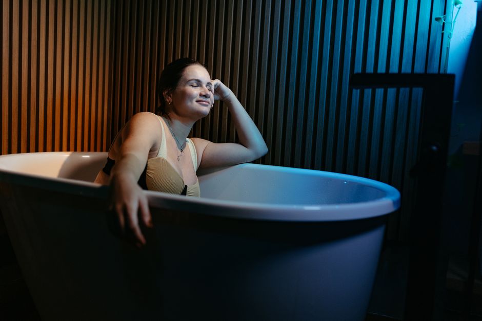 Mulher desfrutando de um momento de relaxamento em um banho de banheira, simbolizando autocuidado e bem-estar.