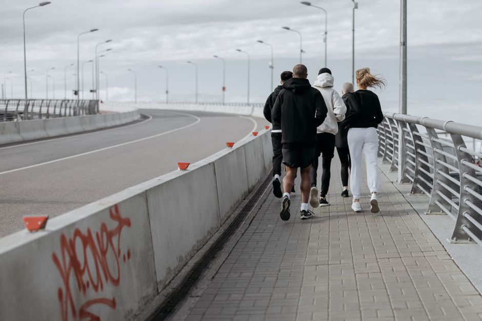 Grupo de jovens caminhando em uma ponte com céu nublado ao fundo, transmitindo uma sensação de liberdade e conexão ao ar livre.