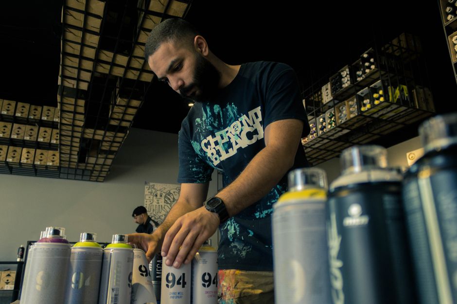 Homem organizando e avaliando latas de tinta em loja de materiais de construção ou loja de artesanato.