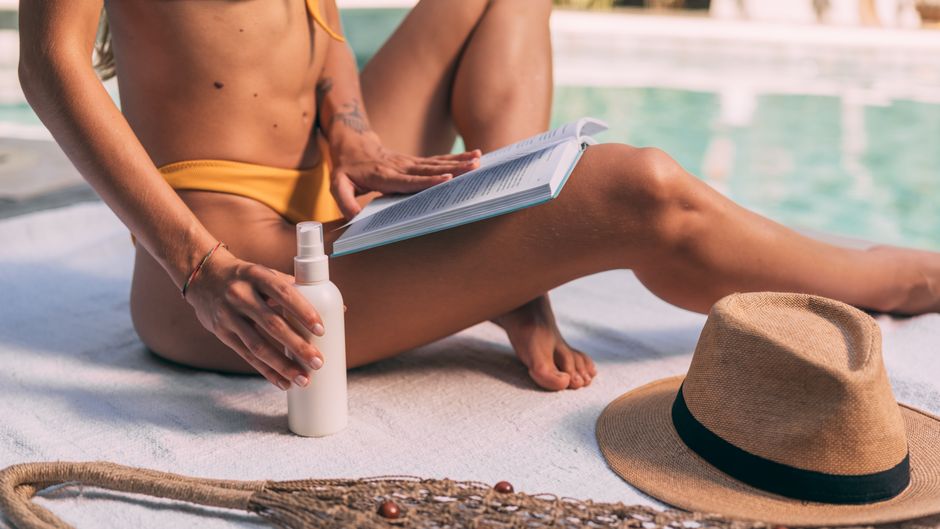 Pessoa de biquíni lendo um livro à beira da piscina, aproveitando um momento de lazer ao ar livre.