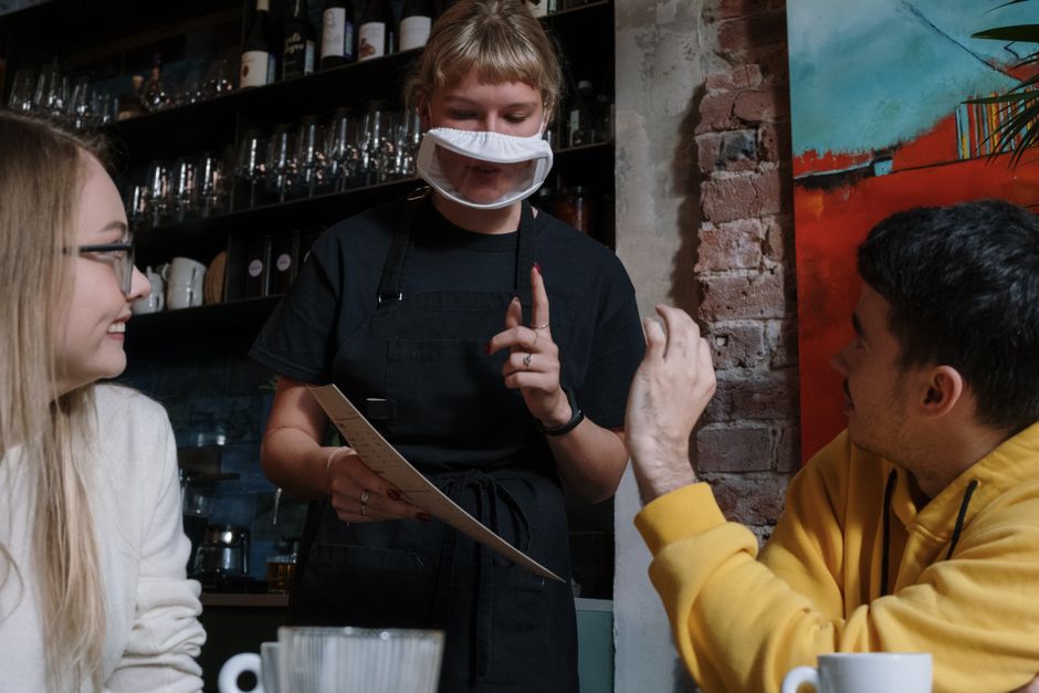 Garçon e garota conversando com garçonete em um restaurante, evidenciando interação e atendimento ao cliente.
