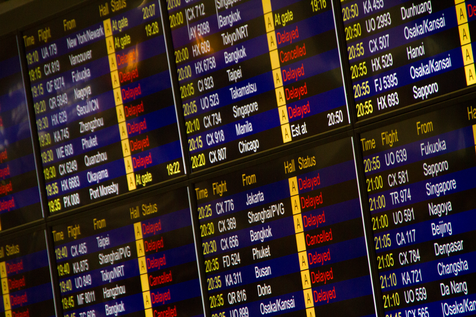 Painel de voos em aeroporto indicando partidas, atrasos e cancelamentos, representando o setor de transporte aéreo e logística.