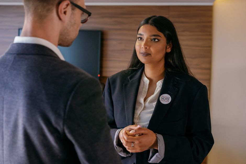 Mulher participando de uma discussão sobre política ou participação cívica em um ambiente corporativo ou institucional.