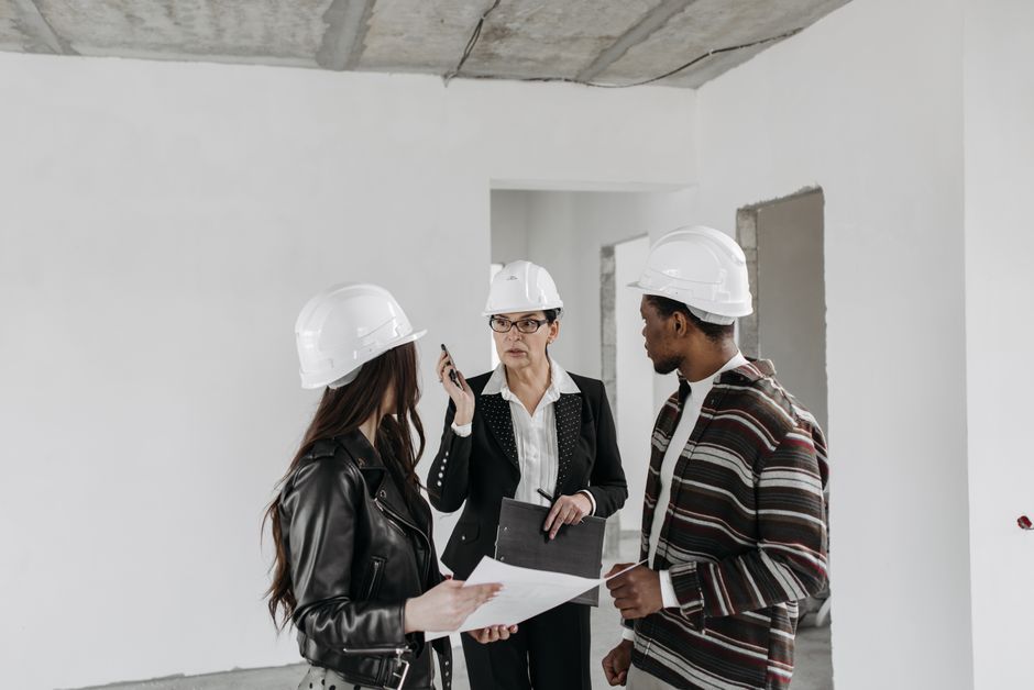 Engenheira e trabalhadores discutindo projetos em um ambiente de construção civil em fase de planejamento ou inspeção.