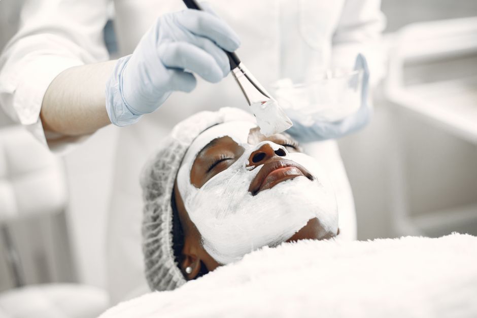 Paciente recebendo um tratamento de limpeza facial em ambiente clínico de estética ou dermatologia.