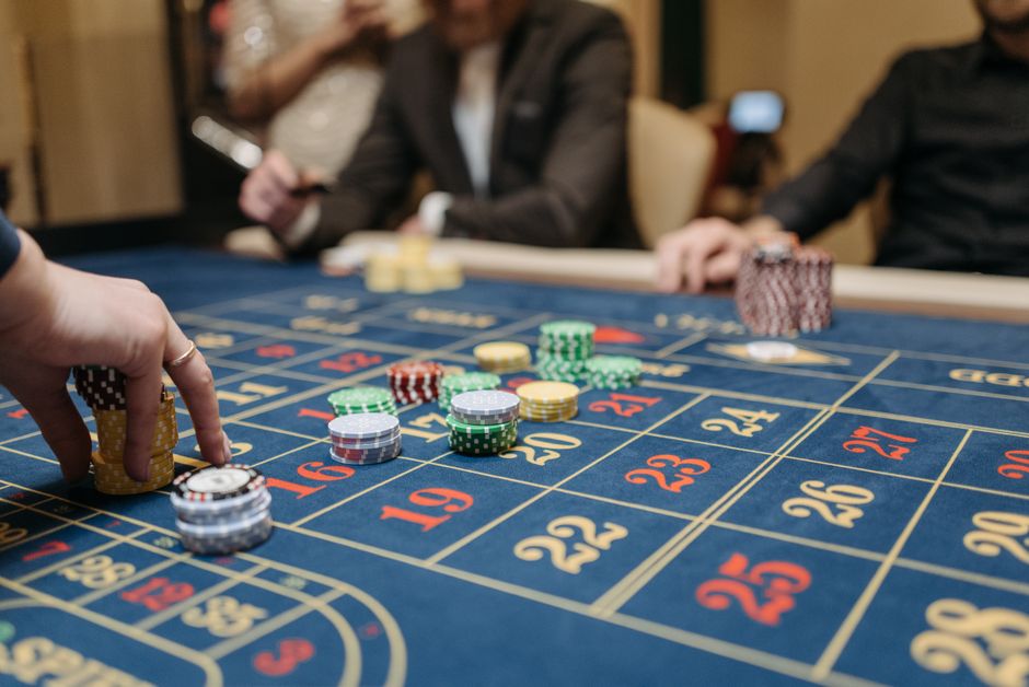 Imagem de uma mesa de roleta em um cassino, com fichas de aposta e pessoas ao redor, capturando o clima de jogos de azar e entretenimento.