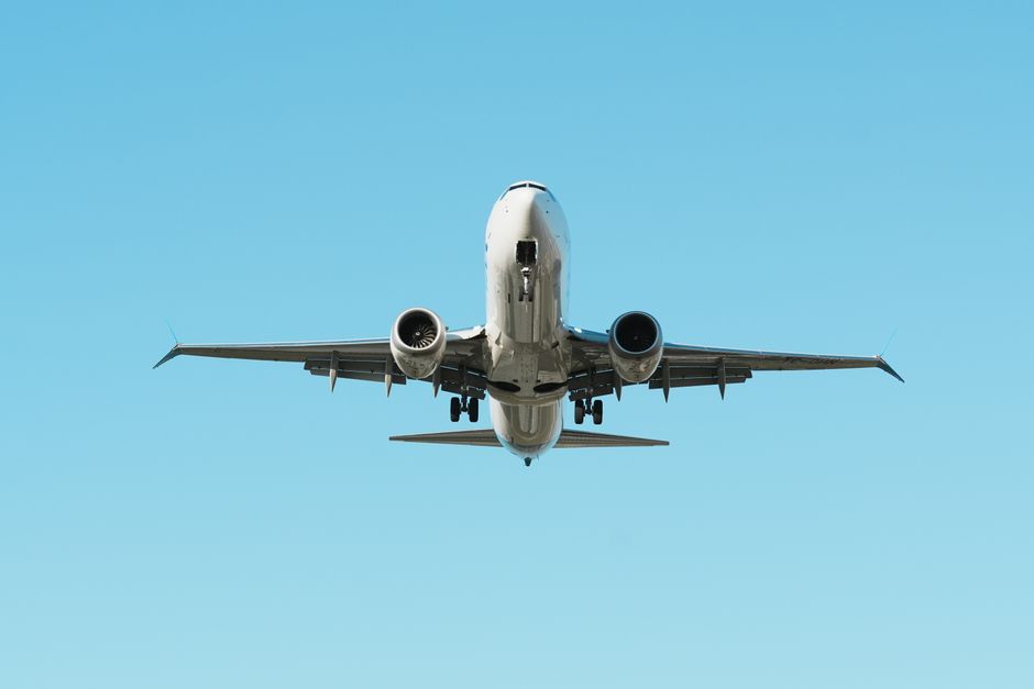 Avião comercial cruzando o céu azul, simbolizando viagens e transporte aéreo.