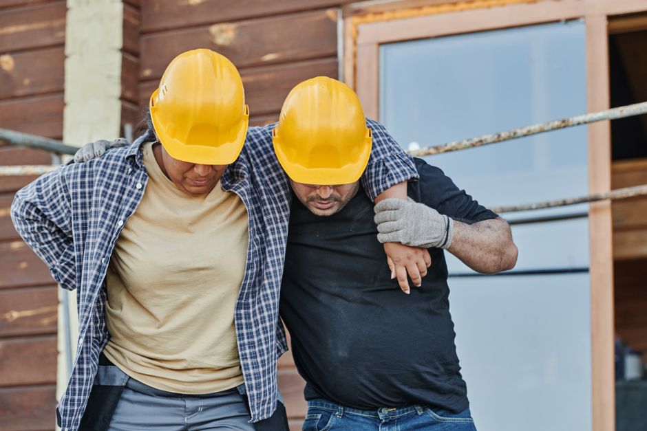 Homens com capacetes de segurança apoiando um ao outro, simbolizando colaboração e apoio em projetos de construção ou trabalho em equipe.