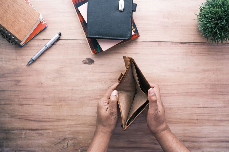 Imagem de uma mesa de trabalho com itens relacionados à organização financeira e planejamento pessoal, com foco na ausência de dinheiro na carteira.