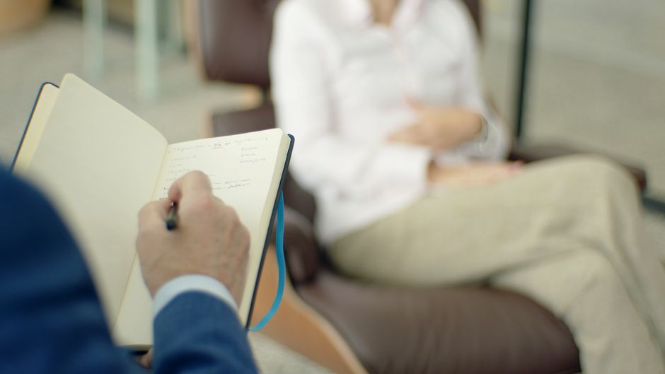 Pessoa fazendo anotações durante uma sessão de terapia ou coaching, com foco no processo de desenvolvimento pessoal e bem-estar emocional.