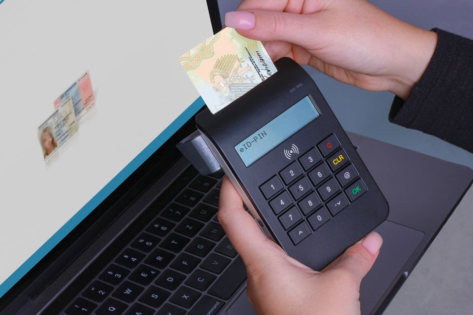 Pessoa realizando pagamento eletrônico de carteira digital com leitor de cartão em ambiente de escritório, destacando segurança e tecnologia financeira.