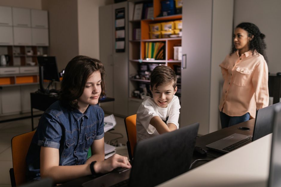 Crianças explorando tecnologia e aprendizado colaborativo em um ambiente educacional moderno.