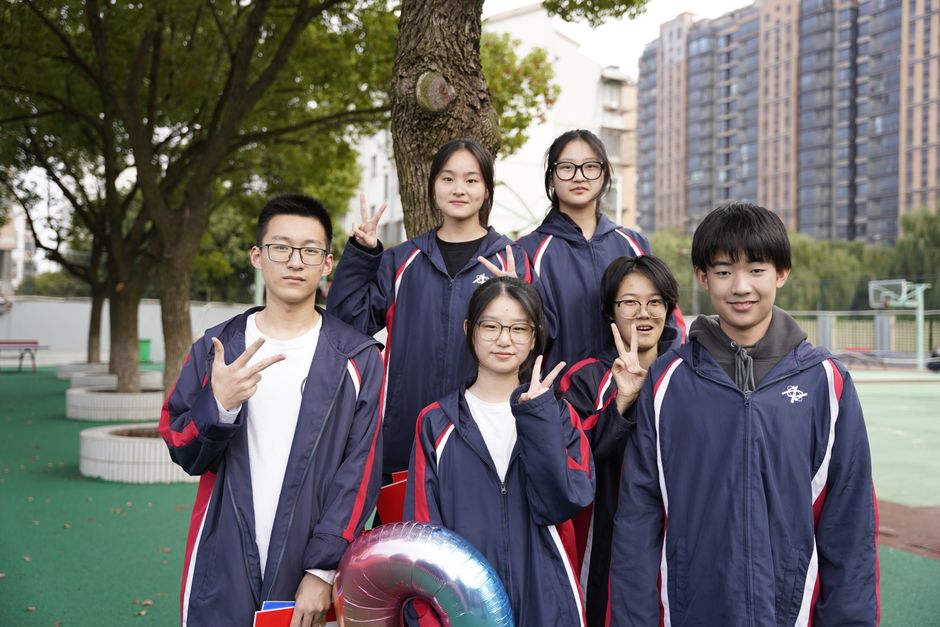 Grupo de estudantes em uniforme escolar ao ar livre, posando e fazendo gestos de paz para uma foto de blog sobre a vida escolar e amizades na adolescência.