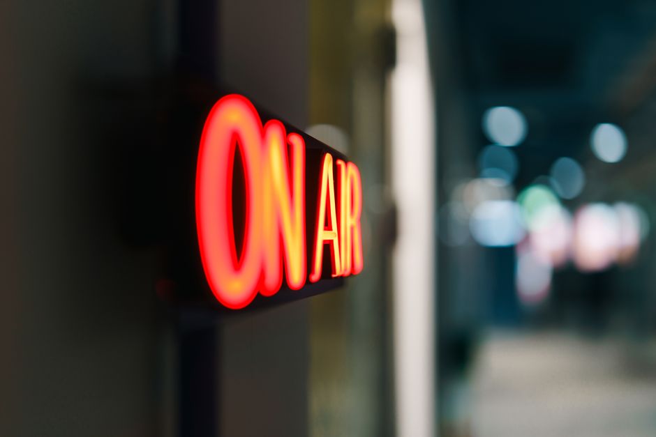 Painel de sinalização em neon indicando transmissão ao vivo, comum em rádios ou podcasts.