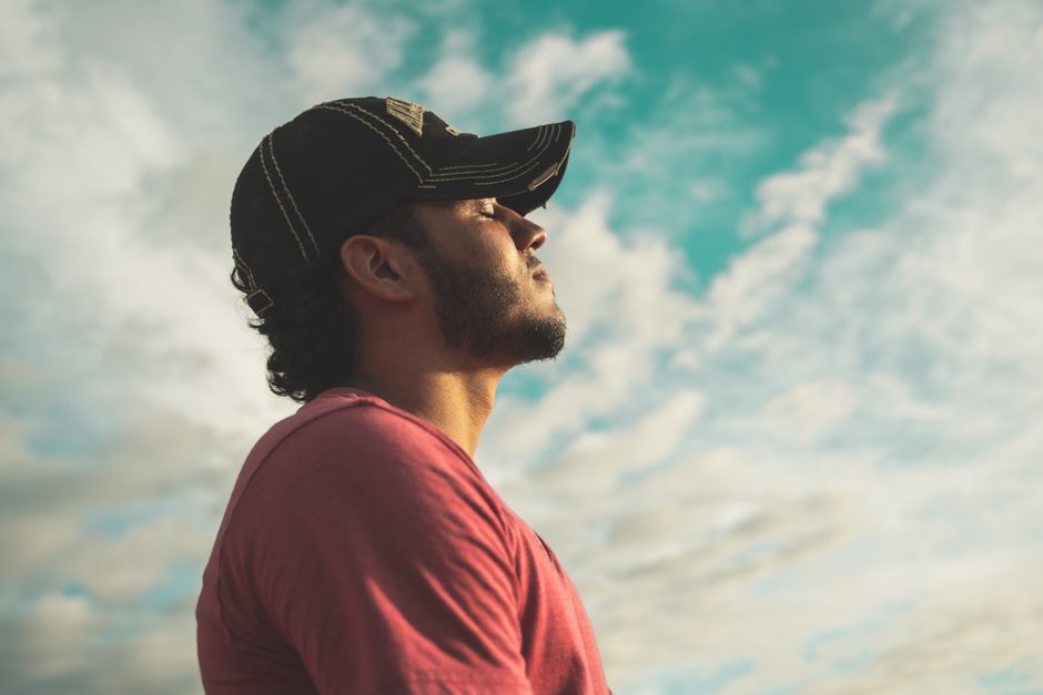Homem contemplando o céu ao ar livre, transmitindo reflexão e conexão com a natureza.