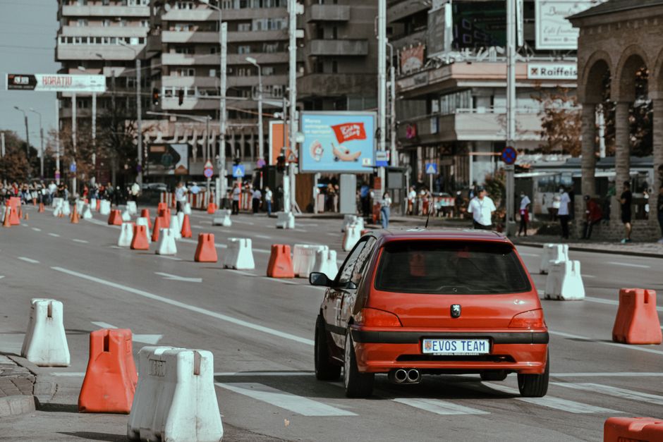Carro participando de uma corrida urbana em uma rua movimentada de cidade, destacando o evento de motorsport na área urbana.