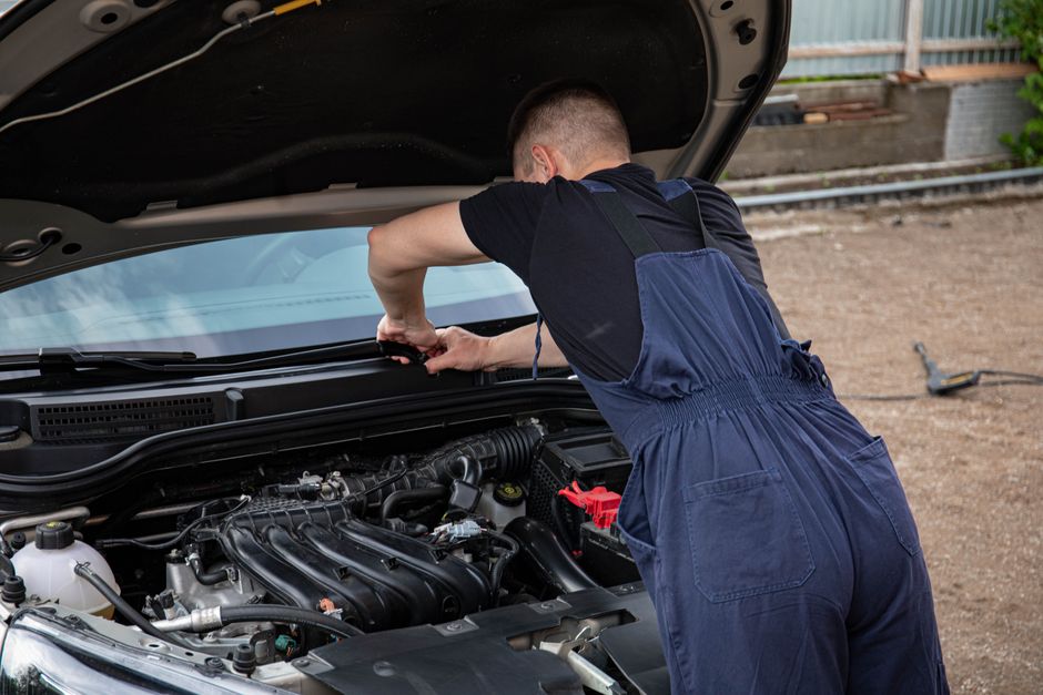 Homem realizando manutenção em um carro, simbolizando cuidado com veículos e habilidades mecânicas.