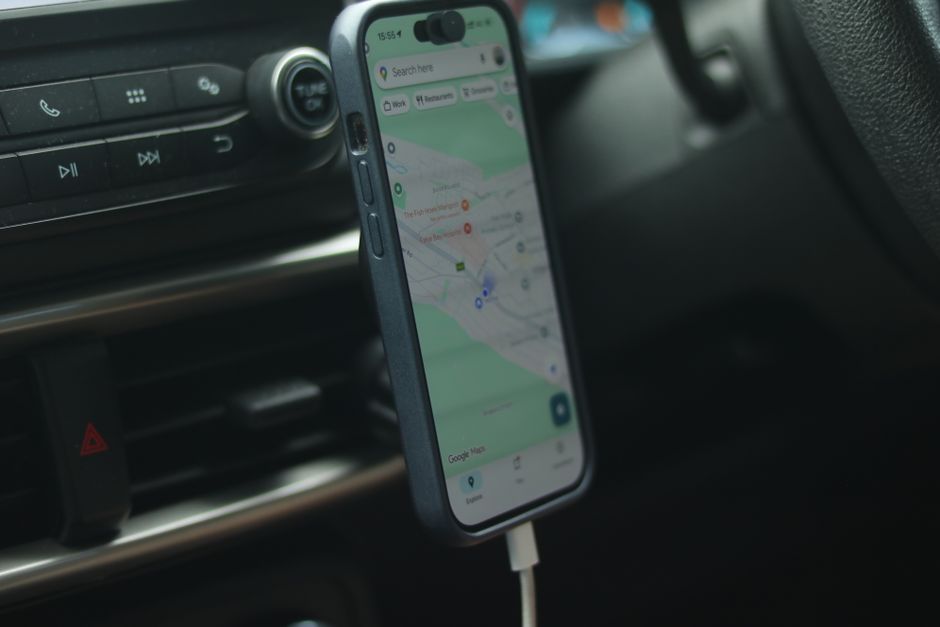 Imagem de um smartphone fixado no painel de um carro, exibindo um aplicativo de mapas, representando mobilidade e navegação durante deslocamentos relacionados a negócios ou viagens.