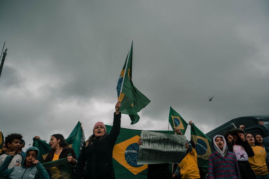 Grupo de pessoas protestando com bandeiras do Brasil em um evento de manifestações civis sob céu nublado.