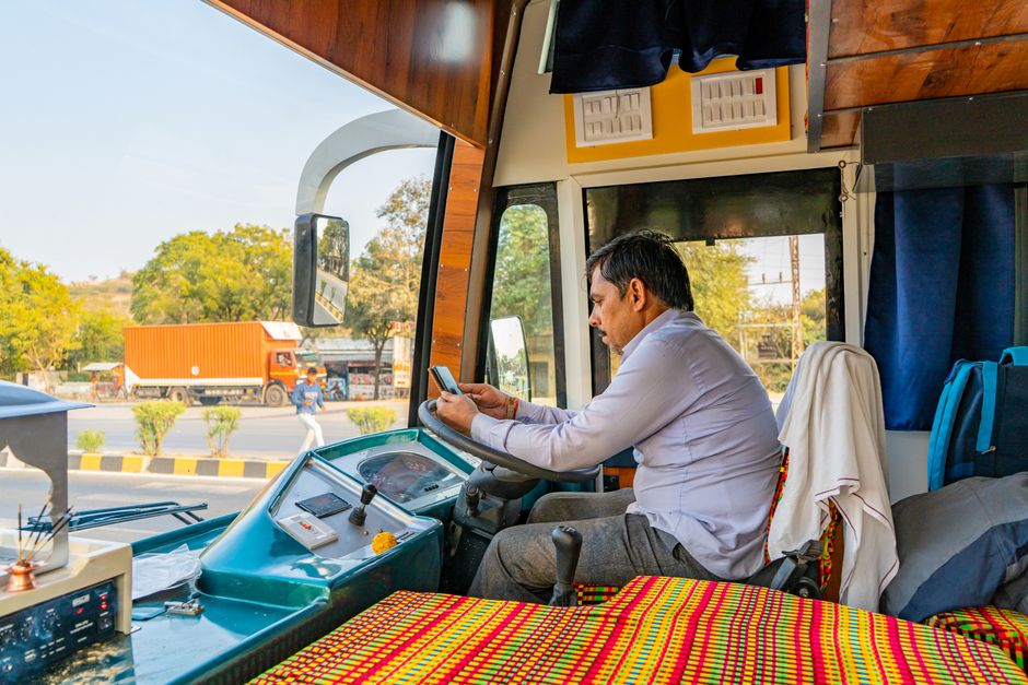 Profissional utilizando o celular dentro de um ônibus, representando mobilidade e tecnologia no transporte público.