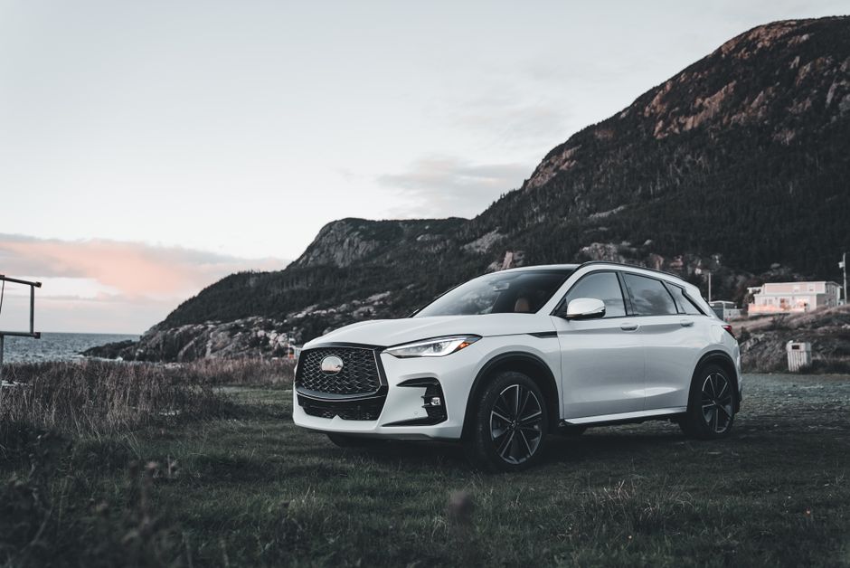 Carro SUV branco estacionado em uma paisagem de natureza com montanhas ao fundo, ideal para ilustrar temas sobre viagens, aventuras ou transporte sustentável.
