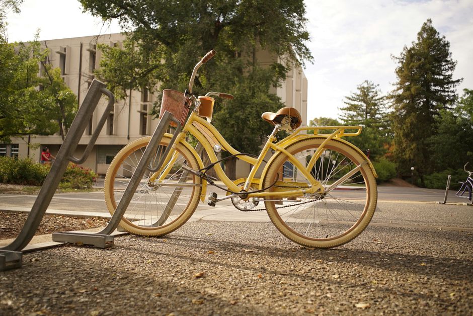 Bicicleta antiga estacionada em uma área urbana, cercada por árvores e edifícios, transmitindo uma atmosfera tranquila ao ar livre.