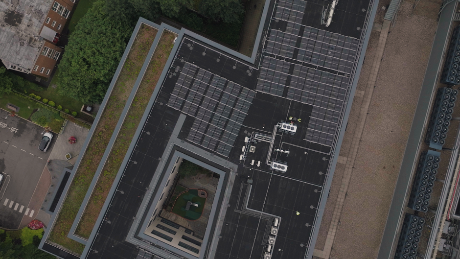 Imagem aérea de um prédio com painéis solares no telhado, destacando a sustentabilidade e energia renovável em edifícios comerciais.