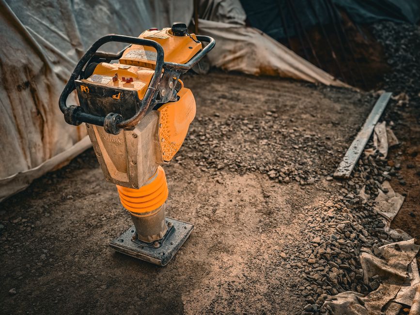 Ferramenta de compactação de solo em um ambiente de construção, destacando o processo de preparação do terreno.