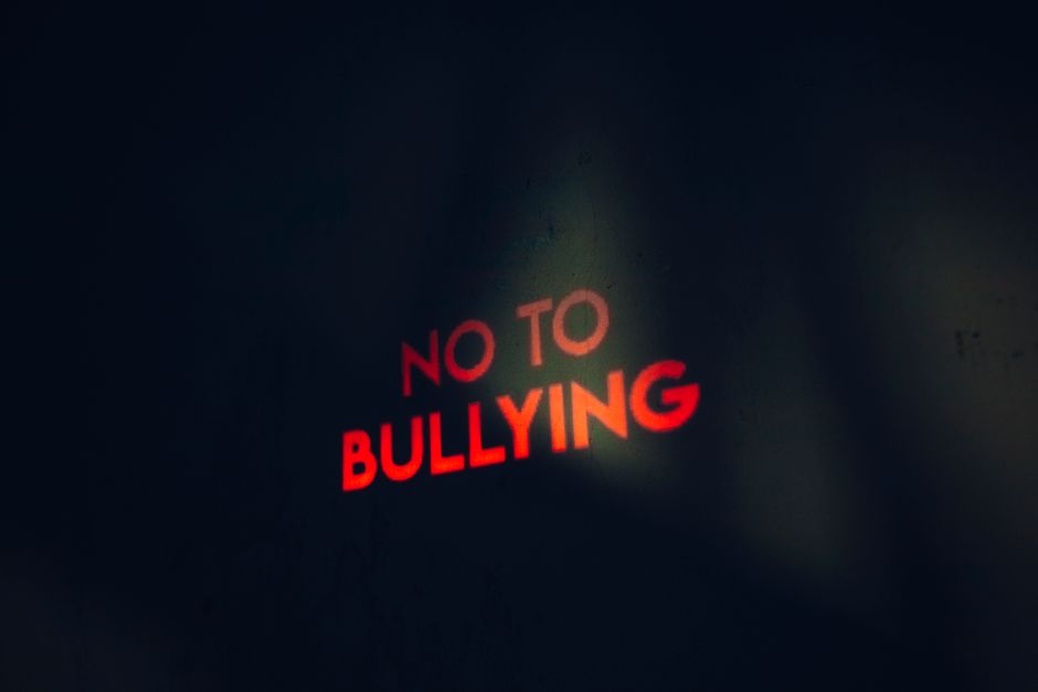 Mensagem contra o bullying escrita com luz LED em uma parede escura, promovendo a conscientização e combate ao bullying.