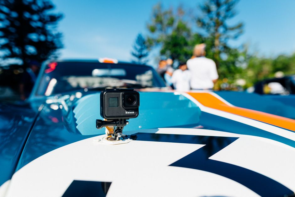 Câmera de ação instalada em um carro de corrida durante um evento automobilístico ao ar livre.