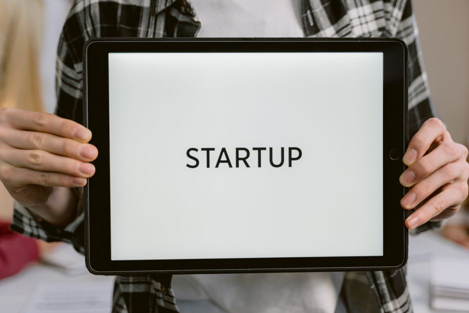 Pessoa segurando um tablet com a palavra 'STARTUP' na tela, representando empreendedorismo e inovação.