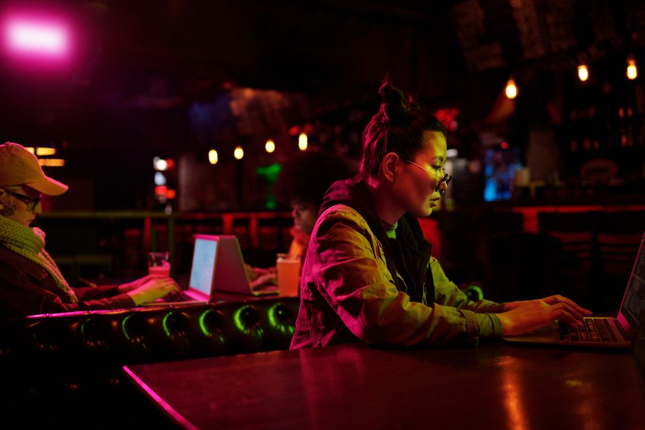 Jovens concentradas trabalhando em computadores em um ambiente com iluminação suave e tom futurista.