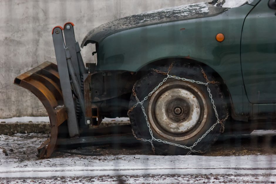 Carro antigo com pneus presos por correntes, demonstrando abandono ou risco de acidentes.