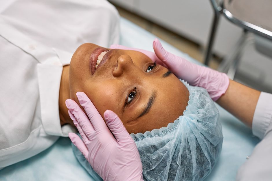 Paciente em procedimento médico facial, recebendo avaliação ou tratamento estético, em ambiente clínico.
