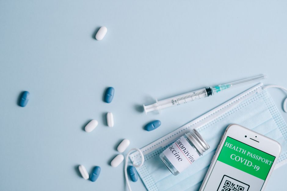 Imagem relacionada à saúde e ao combate à COVID-19, com medicamentos, máscara e passaporte de saúde à disposição.