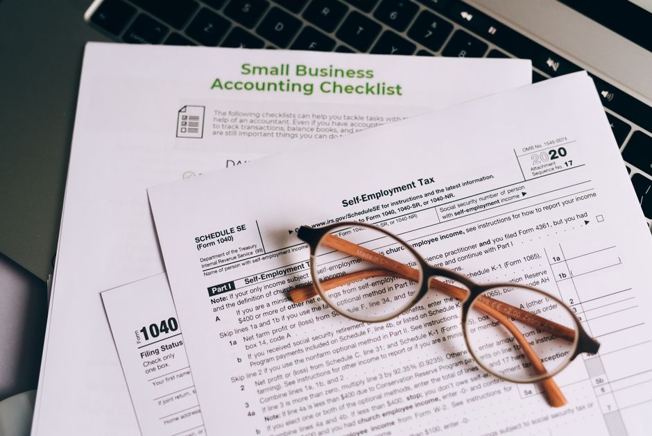 Documentos essenciais para a gestão financeira de pequenos negócios com óculos de leitura sobre uma mesa de trabalho.