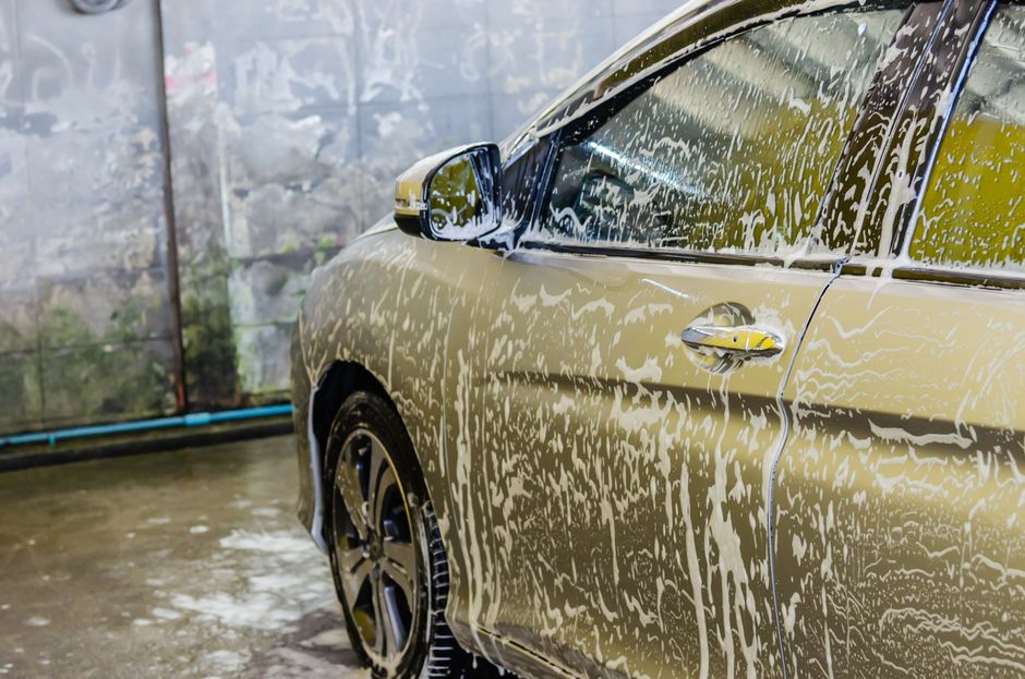 Imagem de um carro sendo lavado com bastante espuma, destacando o processo de limpeza automotiva.