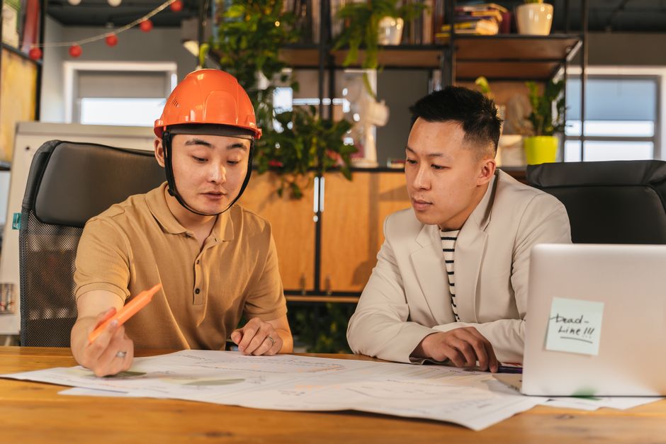 Profissionais de arquitetura discutindo projetos de construção em um ambiente de escritório moderno.
