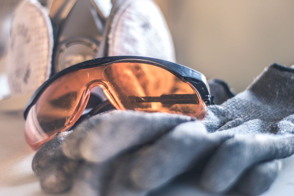 Óculos de proteção esportivos ao lado de roupas usadas para prática de esportes ao ar livre.