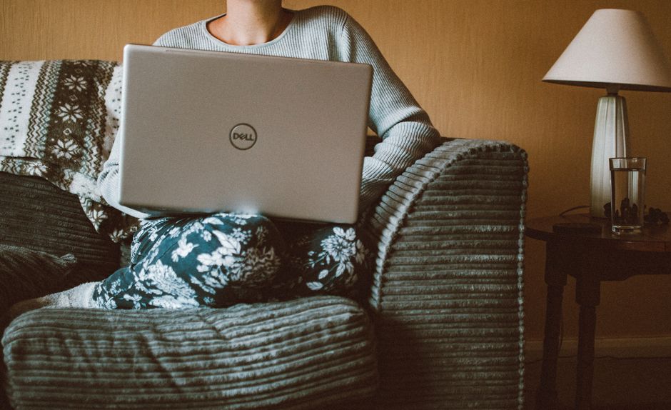 Pessoa trabalhando de casa usando um notebook em um ambiente confortável e acolhedor.