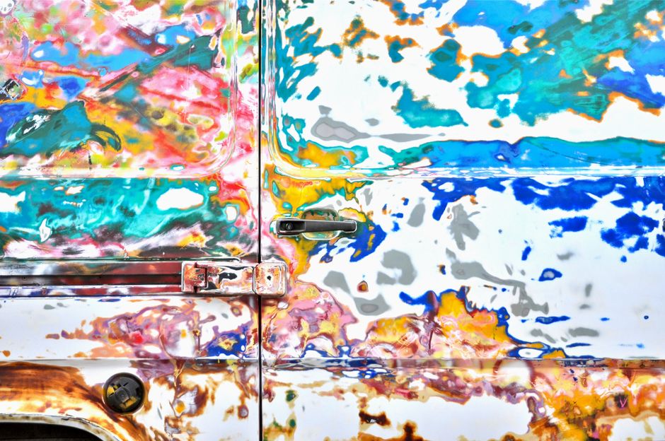 Imagem de uma parede de caminhão com pintura abstrata vibrante e cores variadas, criando um efeito artístico e expressivo.