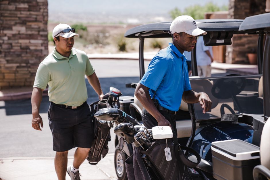 Homens em um campo de golfe ao preparar seus carrinhos de golfe para o jogo em um cenário ao ar livre.