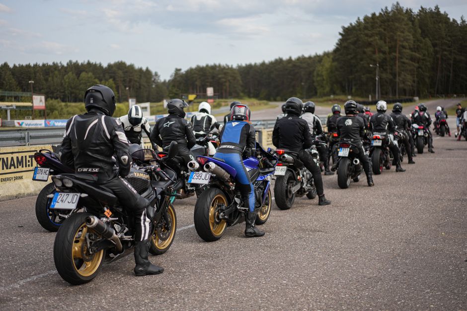 Grupo de motociclistas reunidos em uma pista, pronto para um passeio ou corrida em meio à natureza.
