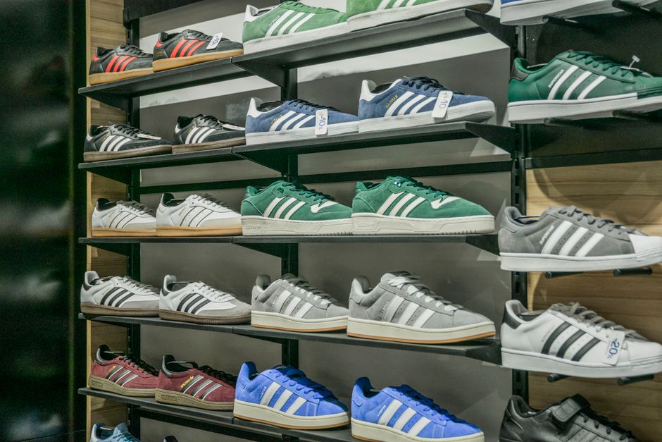 Exposição de tênis esportivos organizados em uma loja, destacando variedade de cores e modelos esportivos.