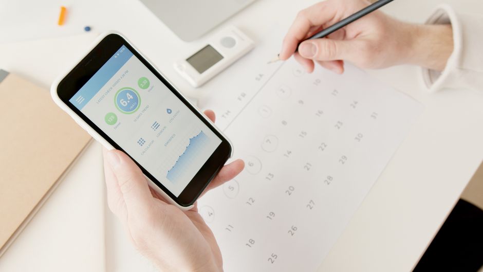Pessoa acompanhando dados de saúde e controle de bem-estar usando aplicativos no celular durante o planejamento de uma rotina saudável.