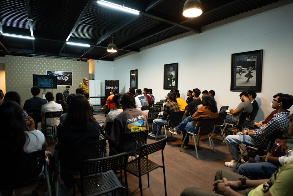 Pessoas assistindo a uma palestra ou evento de capacitação em ambiente interno, com foco em aprendizado e desenvolvimento profissional.