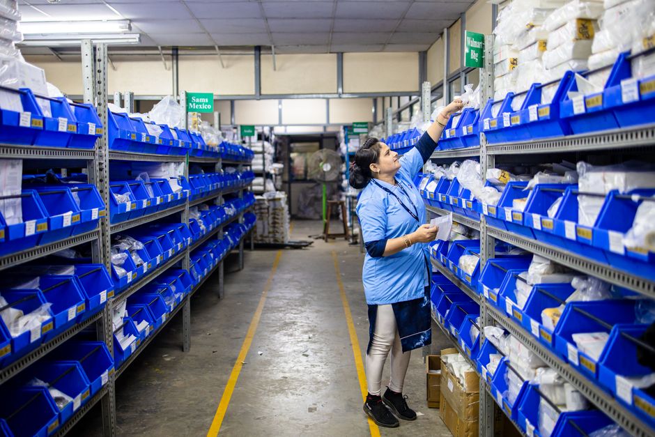 Profissional organizando produtos em estoque de uma loja, representando gestão de inventário e logística.