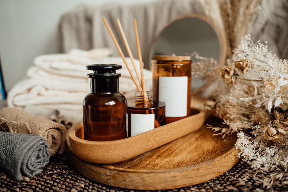Imagem de um arranjo decorativo com frascos de aromatizador e velas em um ambiente de estilo natural e aconchegante, ideal para blogs sobre decoração, bem-estar ou estilo de vida tranquilo.