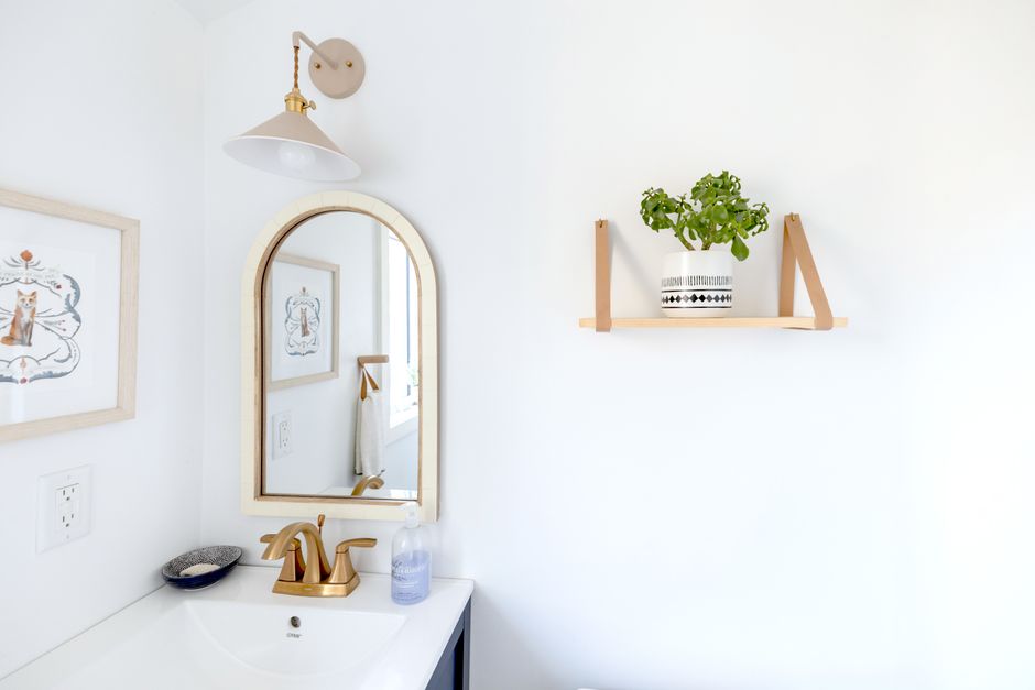Espelho e decoração minimalista em um banheiro com elementos de design clean e plantas na parede.