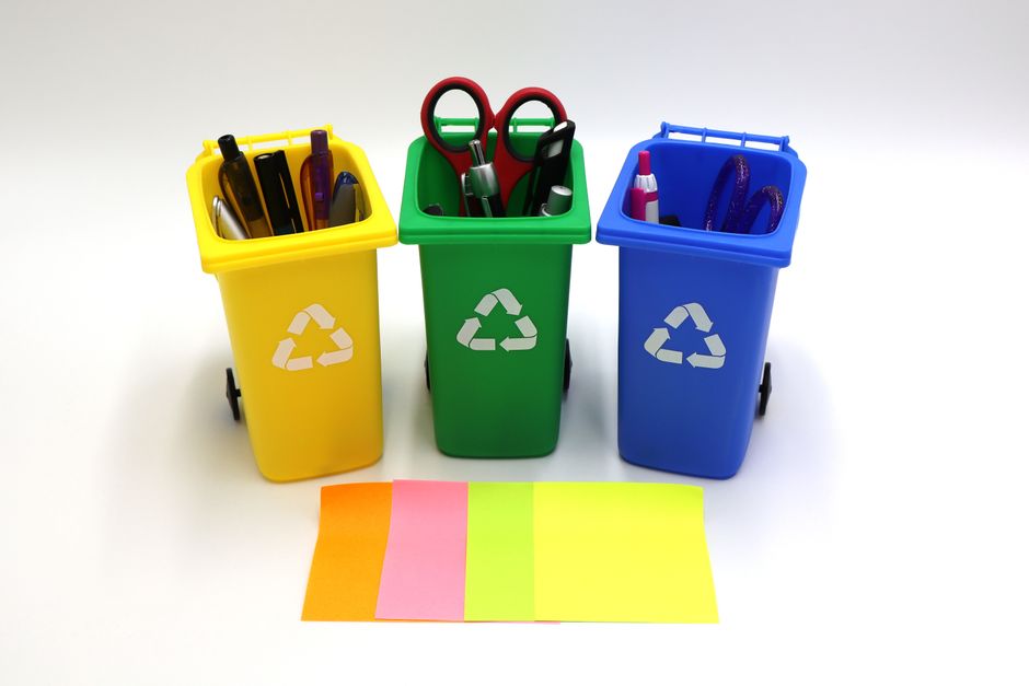 Imagem de lixeiras coloridas usadas para descarte de materiais de escritório, simbolizando sustentabilidade e organização no ambiente de trabalho.